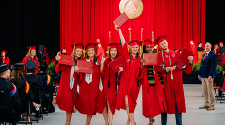 Group of students at commencement posing for a photo looking happy